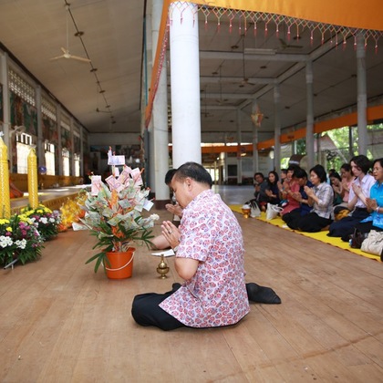 Schüler und Lehrer übergeben Geschenke und Spenden an den Tempel. Ein Mönch singt ein Gebet um alle, die gekommen sind zu segen (deshalb die gefalteten Hände).